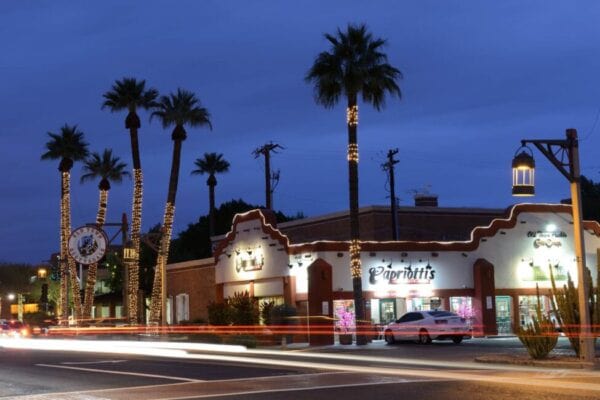 Night view of a street lined with palm trees and a restaurant, in Arizona, with the risk of encountering an uninsured or underinsured driver.