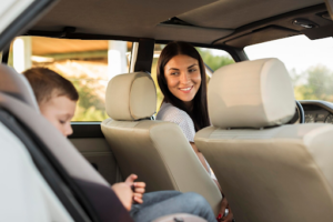 A driver with her kid in the back seat.