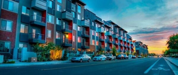 Arizona Bicycle Laws - Row of modern apartment buildings with balconies and parked cars on the street at sunset.