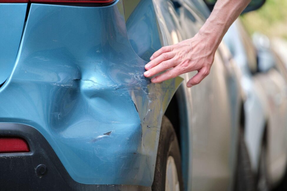 man checking his car after a rear end accident at an intersection