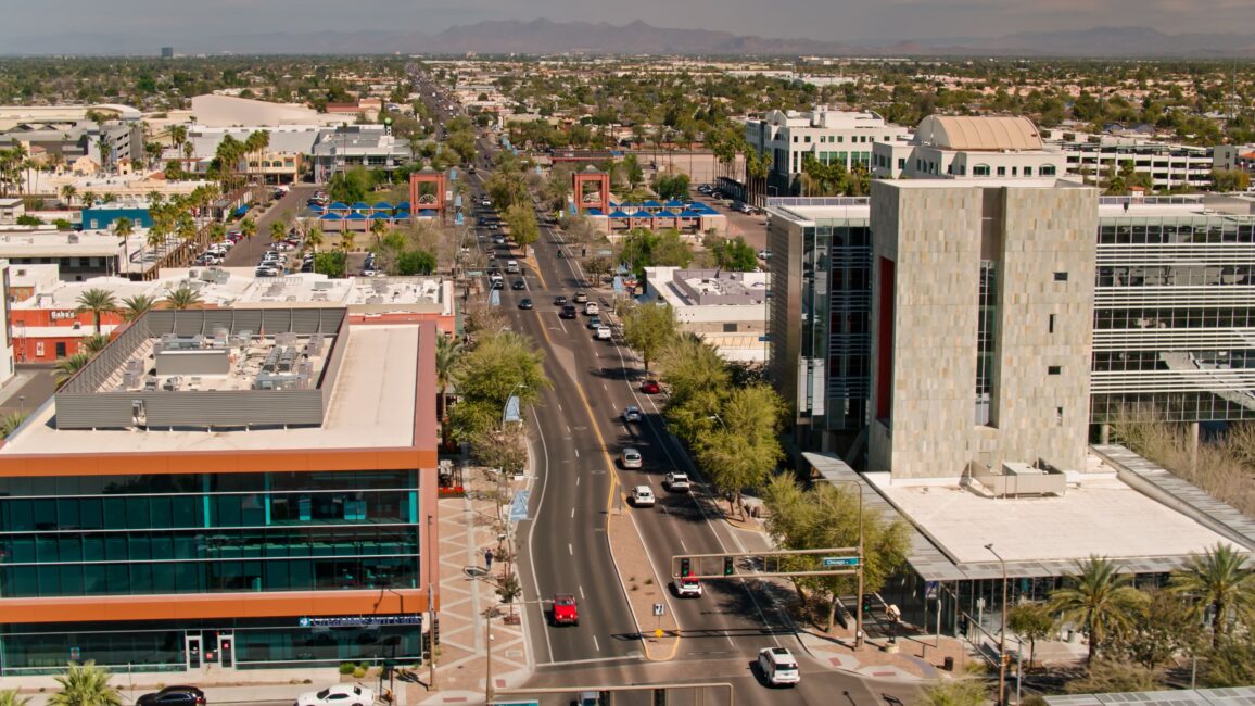 Are personal injury settlements taxable? - Aerial view of a city street lined in Arizona with modern buildings, trees, and parked cars. Mountains are visible in the distance under a partly cloudy sky.