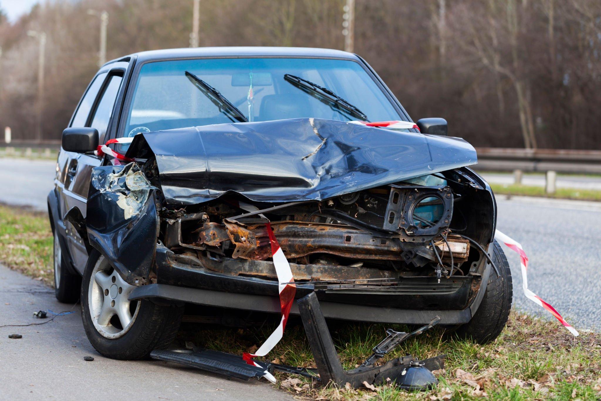 Car completely destroyed after colliding head-on with a pole, with significant damage to the front of the vehicle.