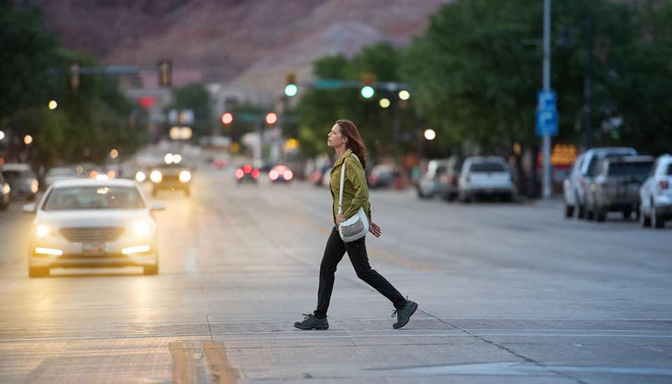 A pedestrian crosses a road, with a car nearly having a pedestrian accidents